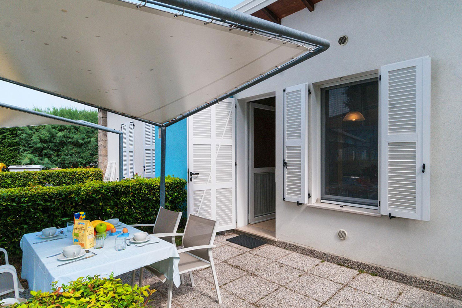 Patio esterno coperto del Bungalow Mare con tavolo, sedie e siepi verdi al Park Gallanti Holiday Village