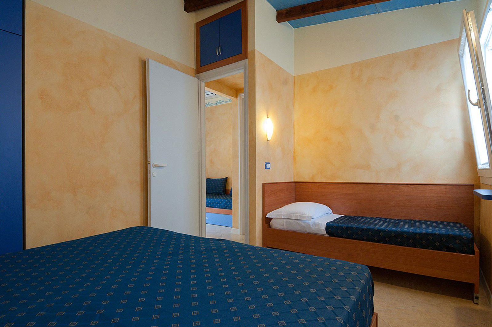 Camera del Bungalow Mare con letto matrimoniale in primo piano e letto singolo al Park Gallanti Holiday Village