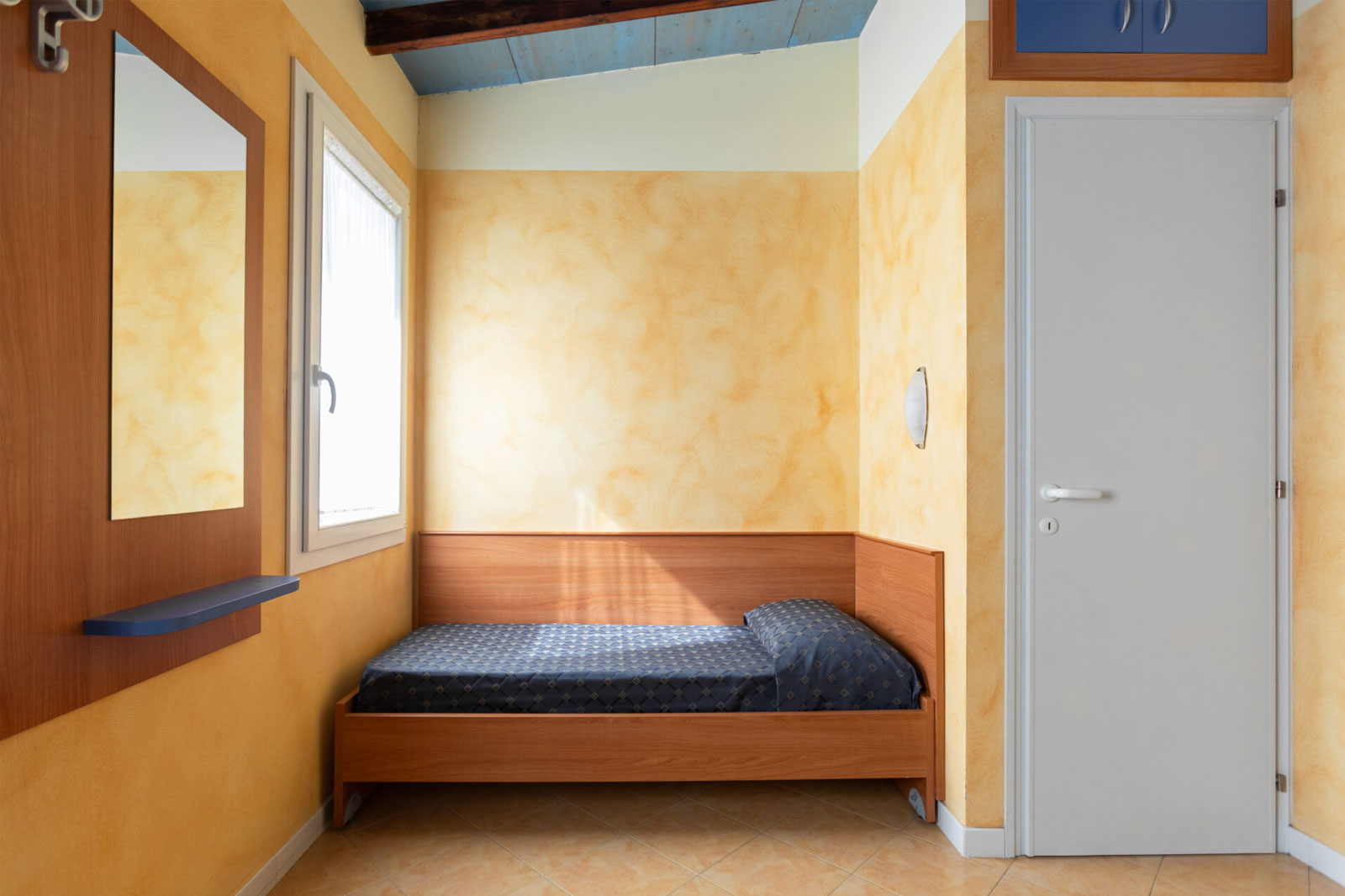 Camera da letto, vista letto singolo con specchio e finestra nella zona giorno del Bungalow Mare al Park Gallanti Holiday Village