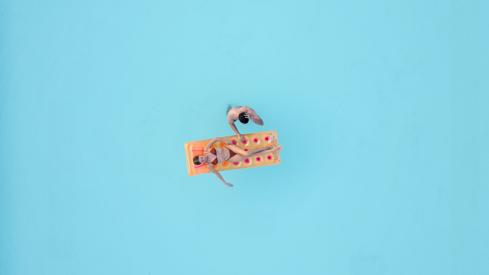 Luftaufnahme eines Paares, das auf einer Luftmatratze im Pool des Feriendorfs Lido di Pomposa entspannt.